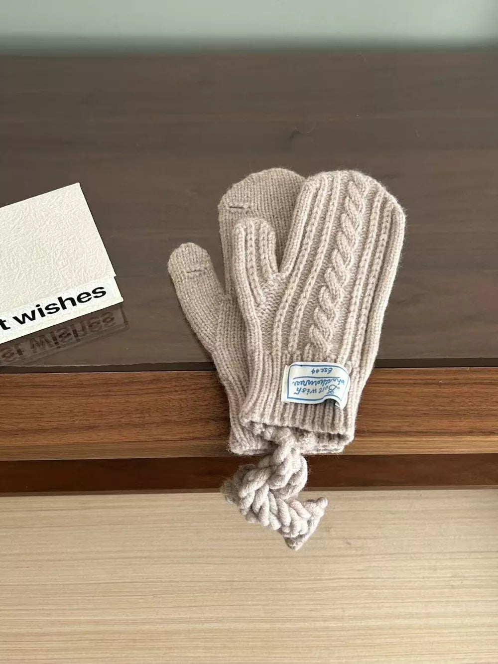 Cozy cable knit acrylic gloves in khaki with braided detail and a decorative rope.