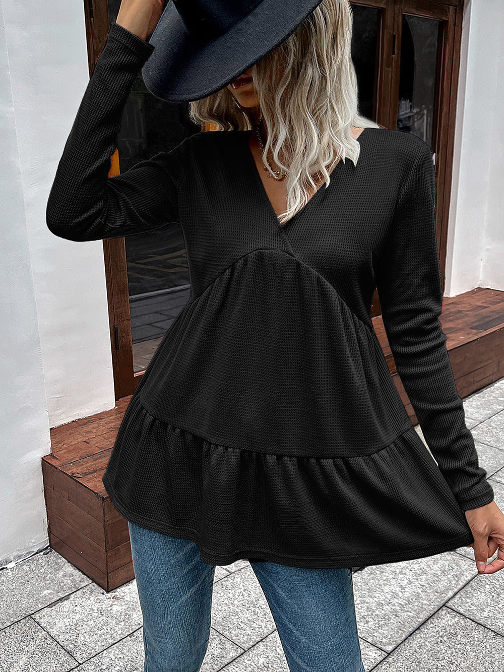 Black waffle knit peplum top with long sleeves and V-neck.