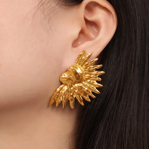 Gold sculptural sunburst earrings with textured rays.