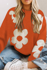 Orange acrylic crewneck sweater with white floral intarsia knit pattern.