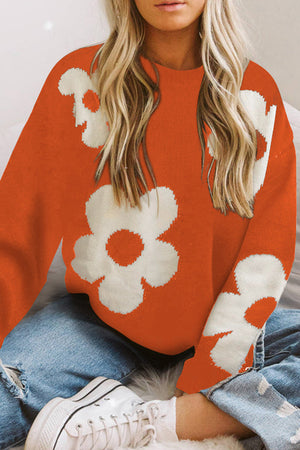 Orange acrylic crewneck sweater with white floral intarsia knit pattern.