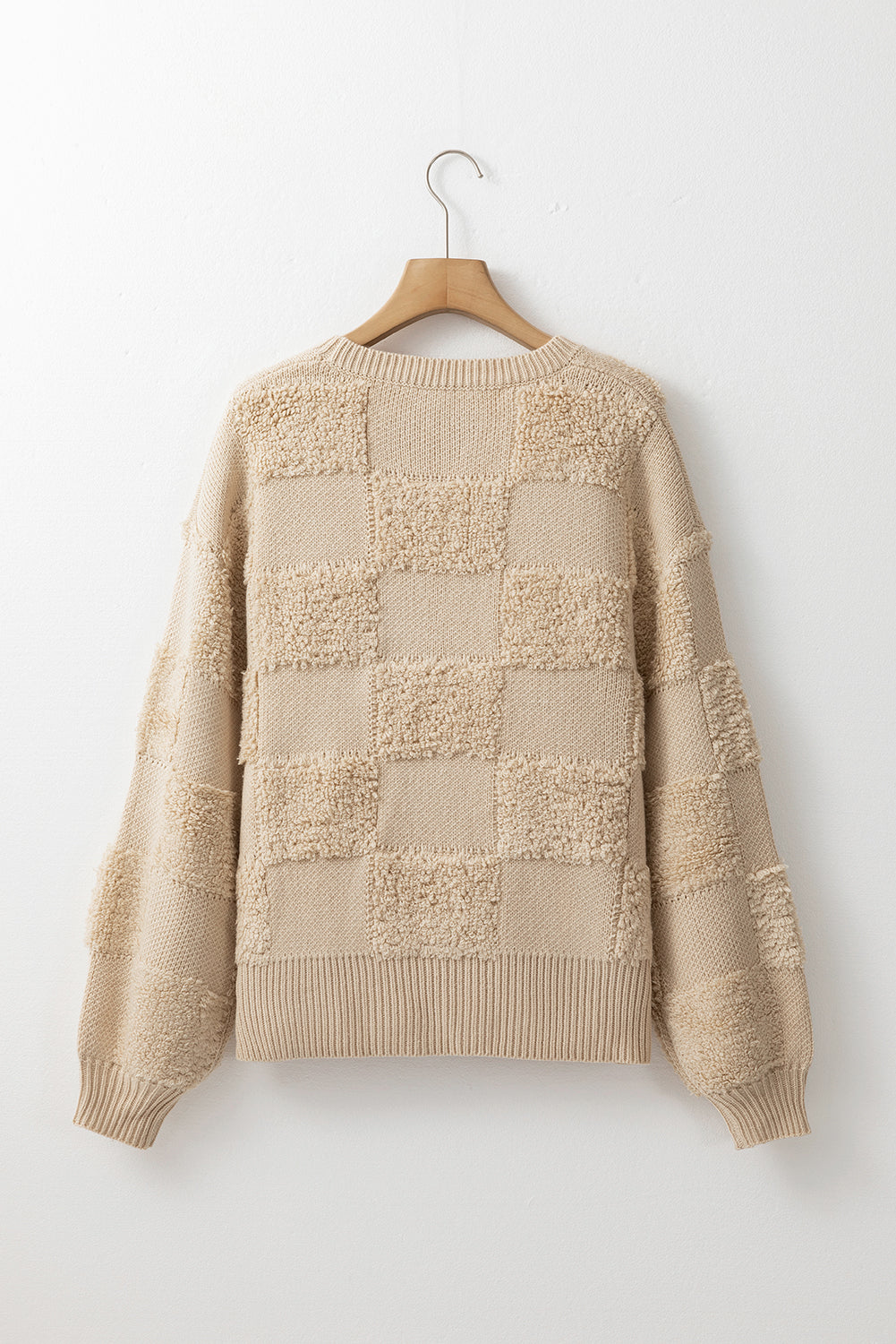 Beige checkerboard knit sweater with textured squares and balloon sleeves.