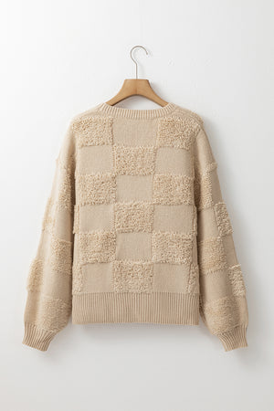 Beige checkerboard knit sweater with textured squares and balloon sleeves.