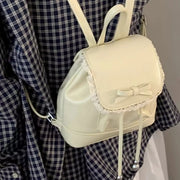 Cream mini backpack with lace trim and bowknot detail, drawstring closure.
