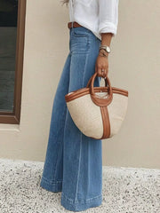 Wide-leg denim jeans in light blue with pockets, styled with a white shirt and straw bag.