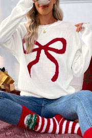 White knit sweater with a large red bow graphic and festive trim.
