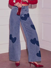 Blue denim high-waist jeans with scattered dark blue heart appliques and wide legs.