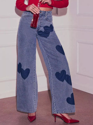 Blue denim high-waist jeans with scattered dark blue heart appliques and wide legs.