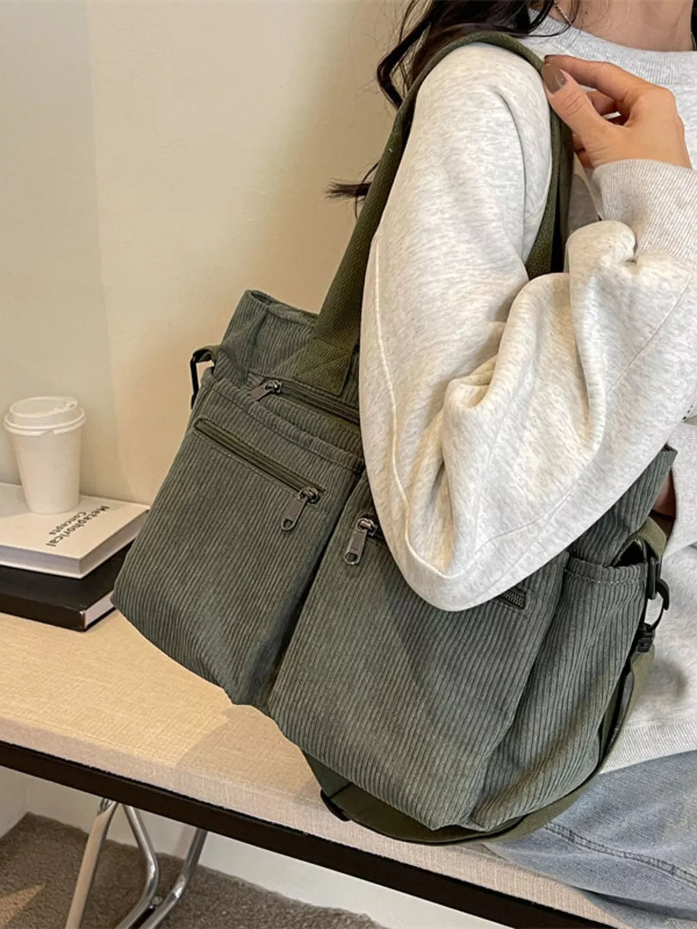 Green corduroy crossbody bag with multiple zippered pockets and adjustable strap.