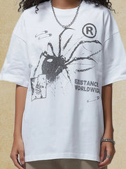 White oversized graphic tee with spider print, safety pins, and text.