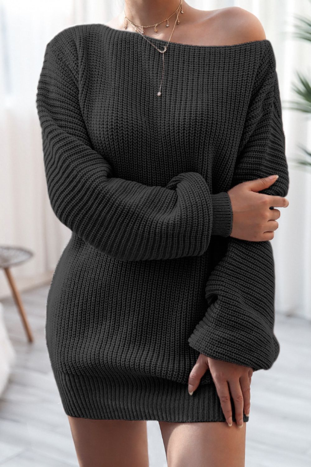 Black off-the-shoulder ribbed knit mini dress with long sleeves and a boat neckline.
