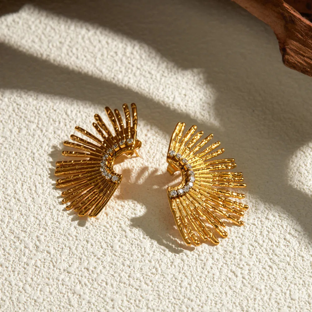Gold sunburst crystal earrings with textured rays and a curved row of clear crystals.