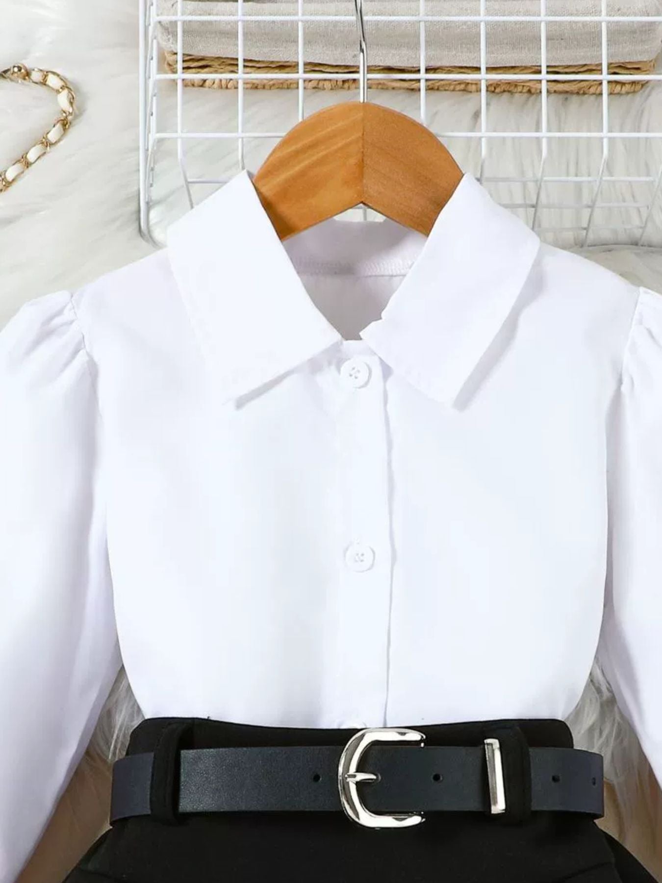 Toddler white collared long sleeve shirt with puff sleeves and a black belted skirt.