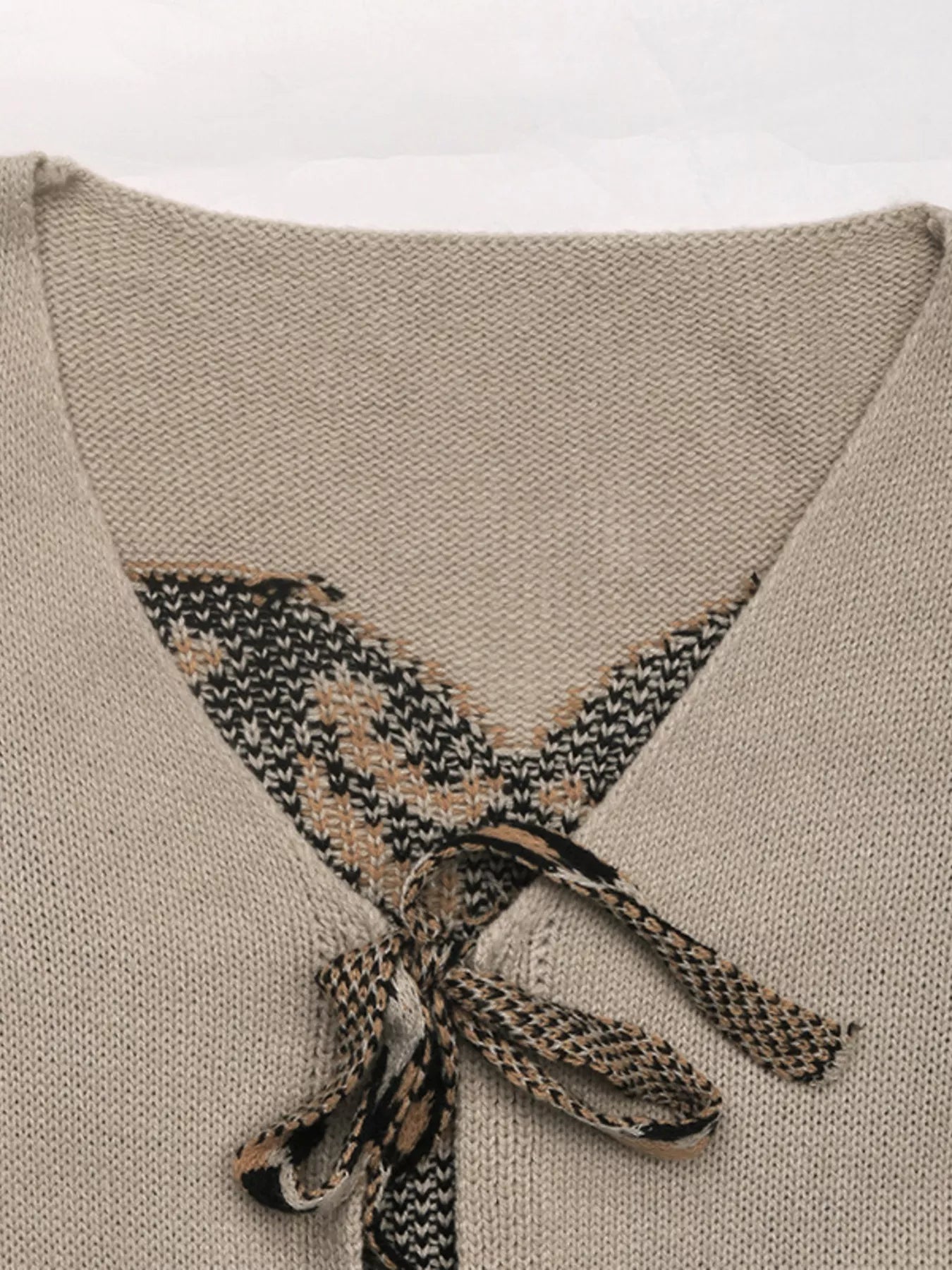 Gray apricot knit cardigan with patterned V-neck and tie front detail.
