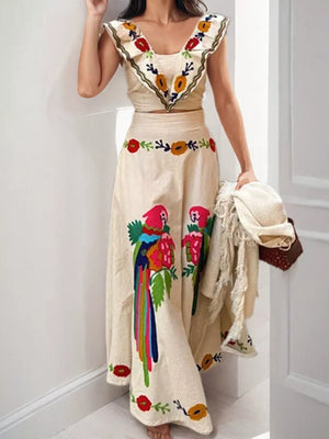 Cream maxi skirt with parrot and floral embroidery, featuring a ruffled V-neck crop top.