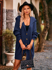 Navy hooded knit cocoon cardigan with button front and pockets, styled with a black hat and quilted purse.