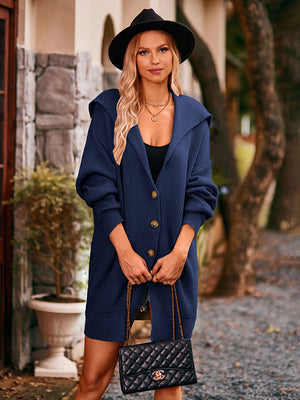 Navy hooded knit cocoon cardigan with button front and pockets, styled with a black hat and quilted purse.