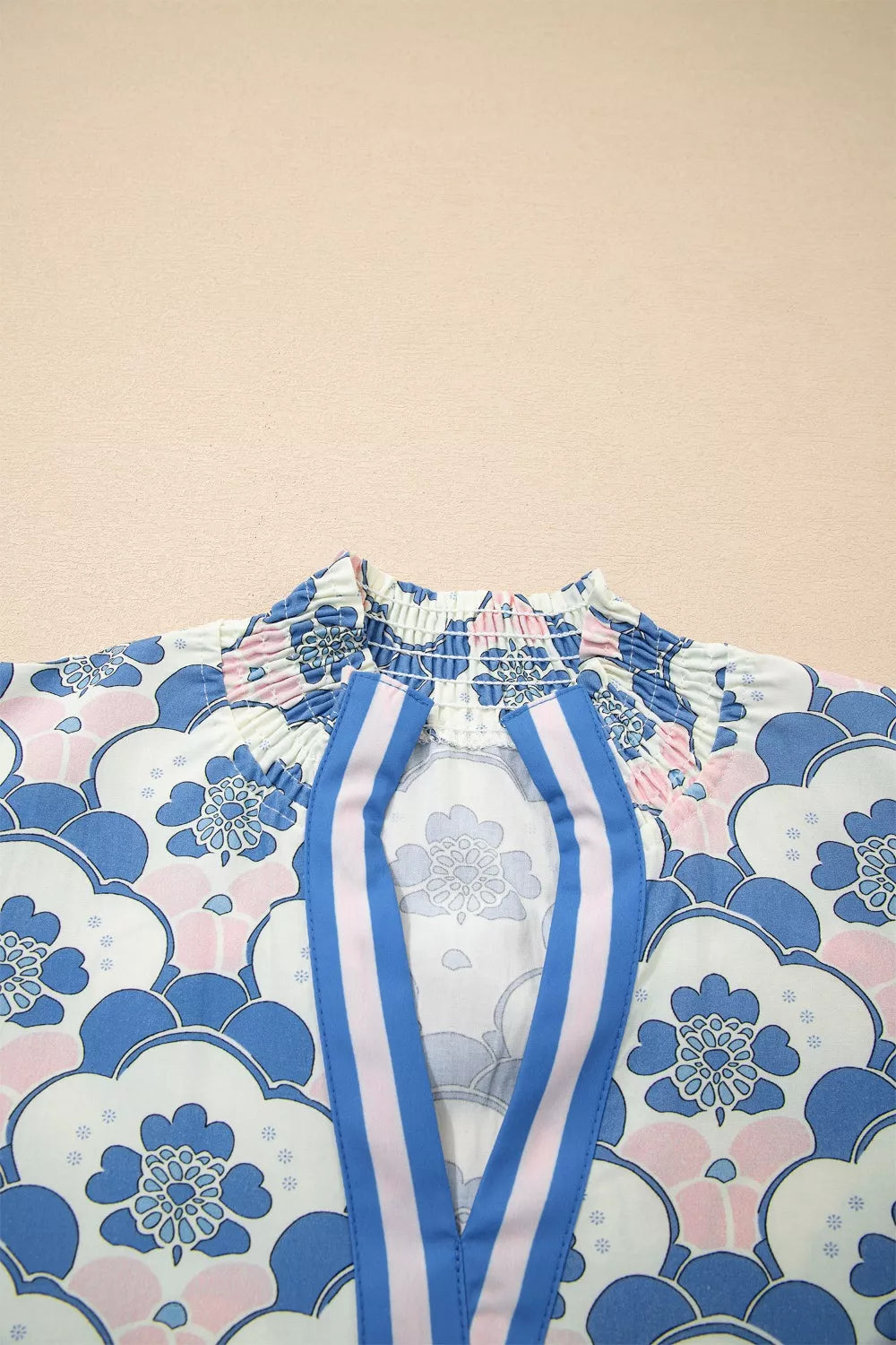 Blouse with floral print, smocked neckline, and blue and pink striped placket.