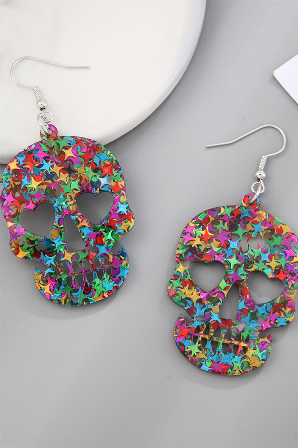 Glitter starburst skull dangle earrings in multicolor acrylic.
