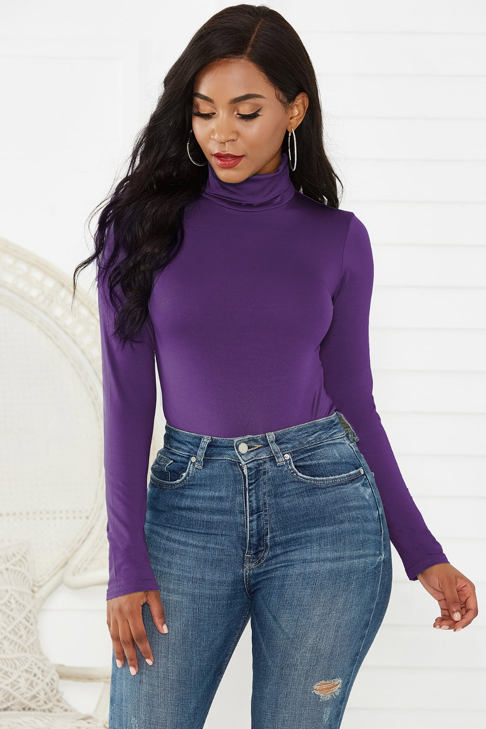 Purple turtleneck thong bodysuit with long sleeves, styled with high-waisted jeans.