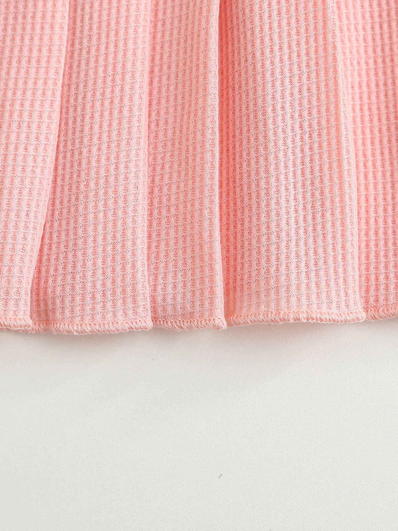 Pink waffle knit baby dress with a pleated hem.