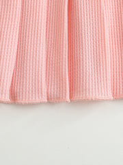 Pink waffle knit baby dress with a pleated hem.