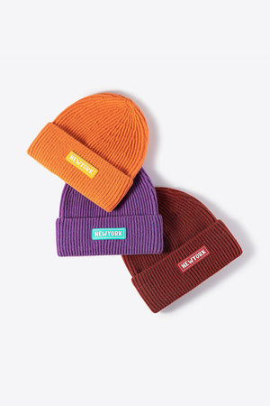 Ribbed acrylic beanies in orange, purple, and rust, each with a New York patch detail.