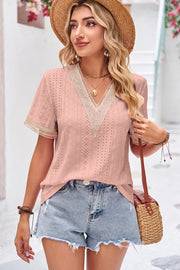 Blush pink eyelet v-neck blouse with lace trim and short sleeves.