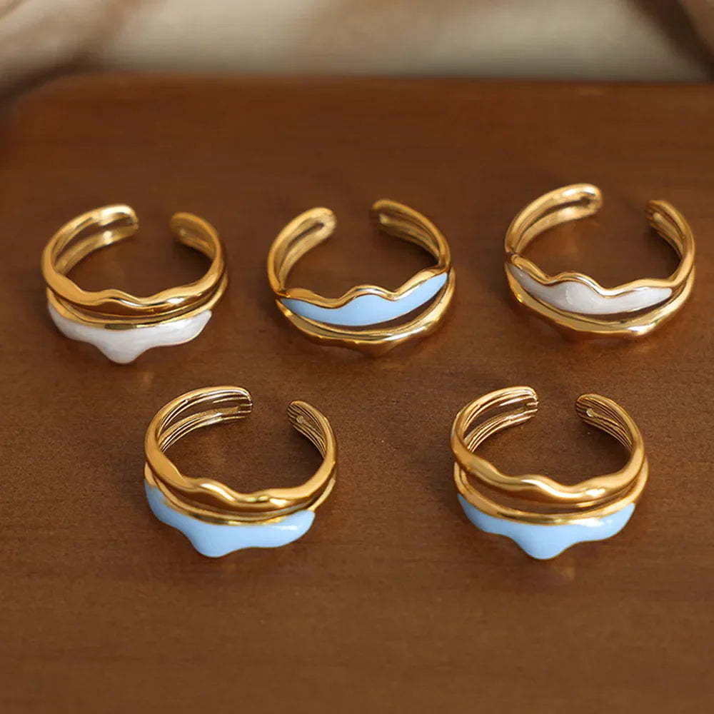 Gold tone rings with sculpted wave enamel in white and light blue.