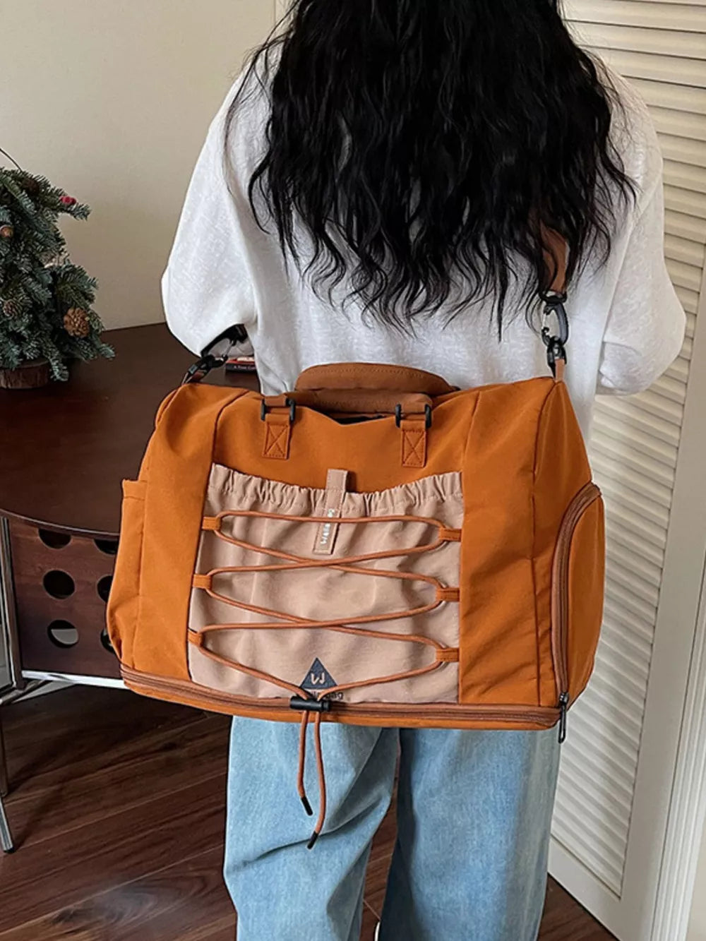 Versatile large nylon duffel bag in orange and beige with bungee cord detail.
