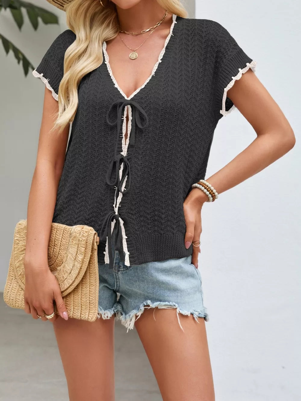 Black tie-front knit cardigan with white trim and short sleeves.