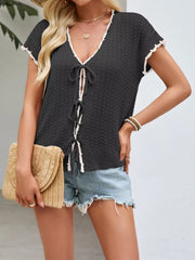 Black tie-front knit cardigan with white trim and short sleeves.