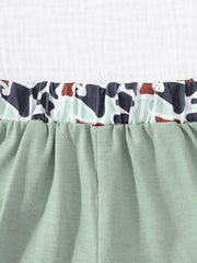 Sage green baby shorts with elastic waistband and camouflage print trim