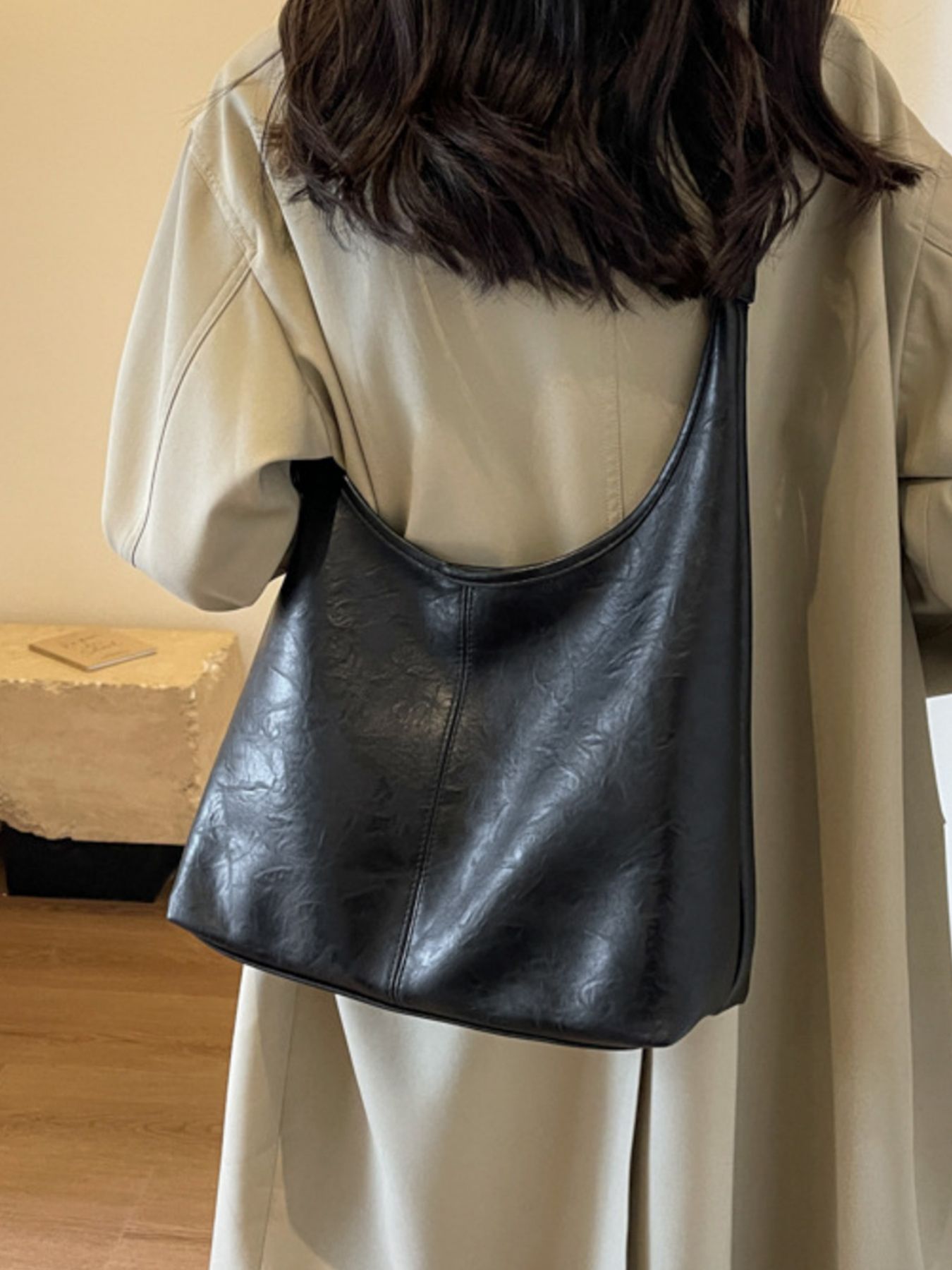 Black faux leather shoulder bag with textured finish and adjustable strap.