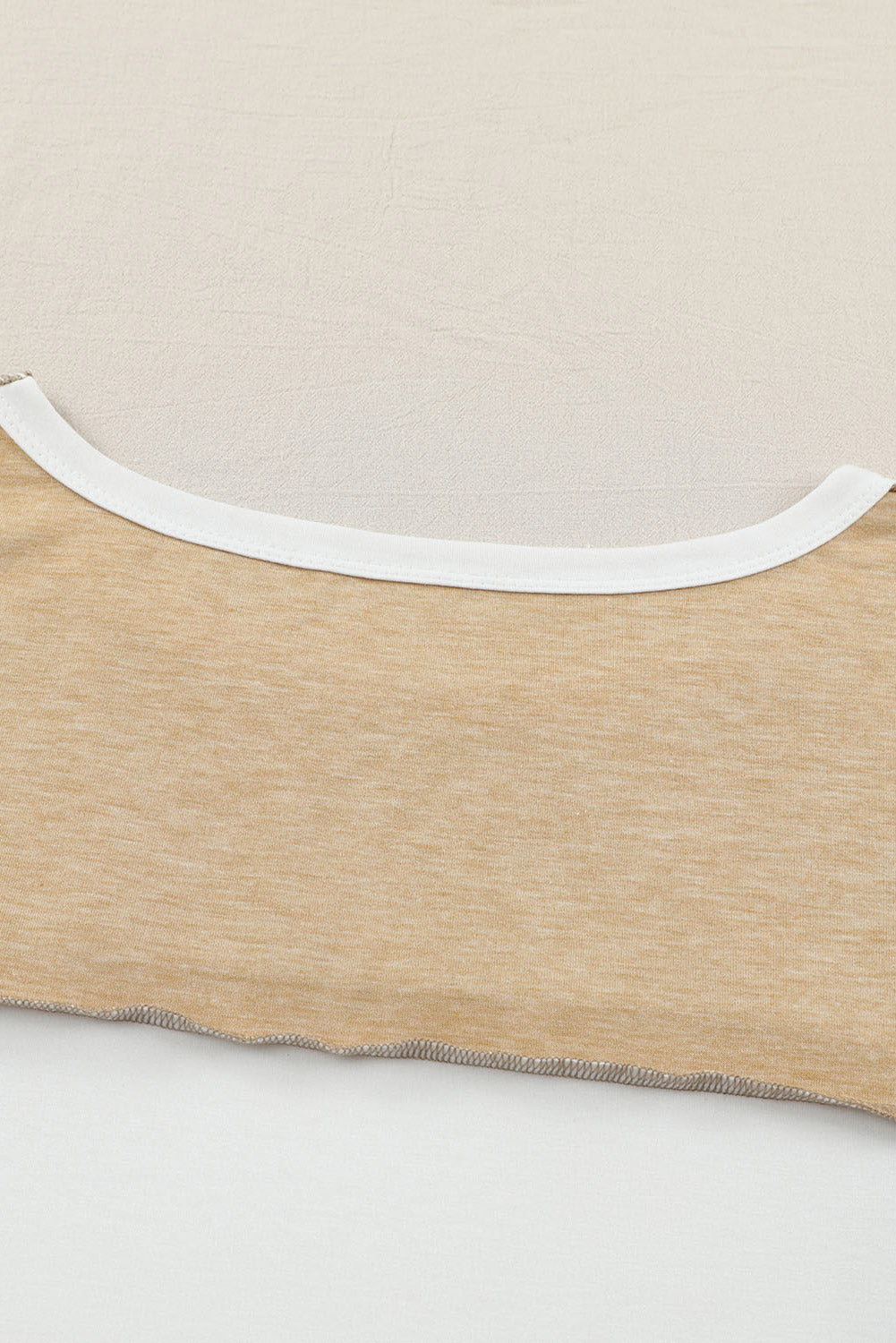 Colorblock knit top in tan with white neckline trim and raw hem detail.