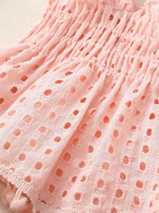 Pink cotton eyelet baby bloomers with smocked waist and pom pom trim.