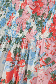 Vibrant floral maxi dress with smocked bodice and flutter sleeves in white with red, blue, and pink flowers.