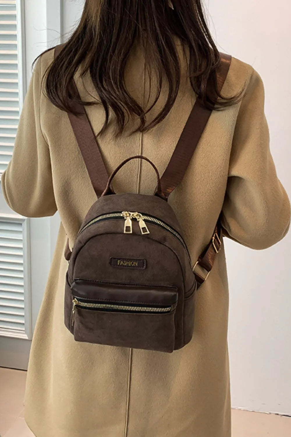 Coffee brown suede mini backpack with golden zips and front pocket.