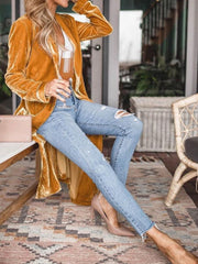 Velvet duster coat in Tangerine with fluid silhouette, worn open over jeans.