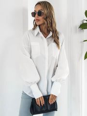 White oversized poplin blouse with blouson sleeves and button front, styled with light wash jeans and a black clutch.