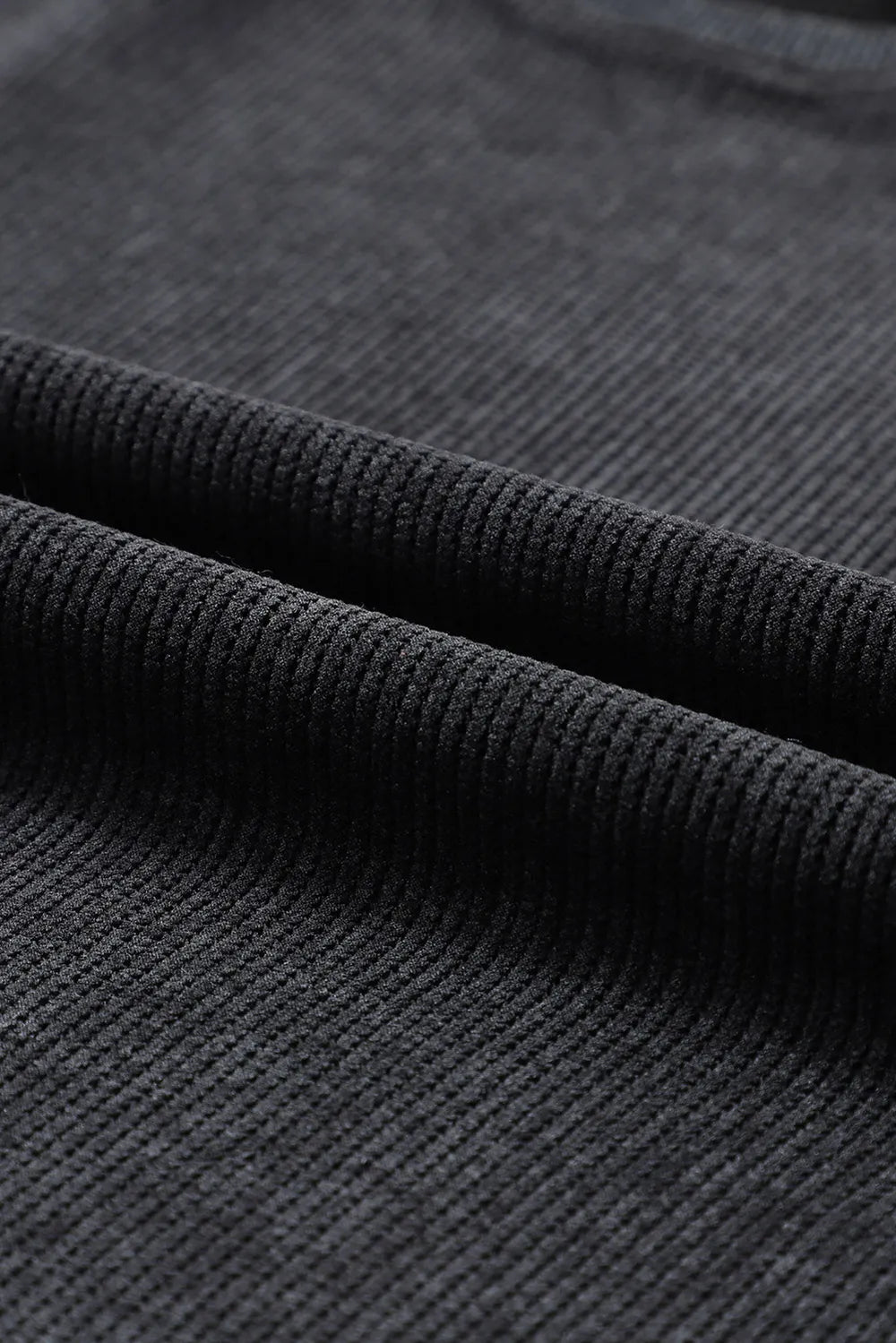 Black ribbed sweatshirt fabric detail showing texture and weave