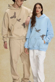 Embroidered flight hoodie in light blue with bird graphic, relaxed fit, and front pocket.