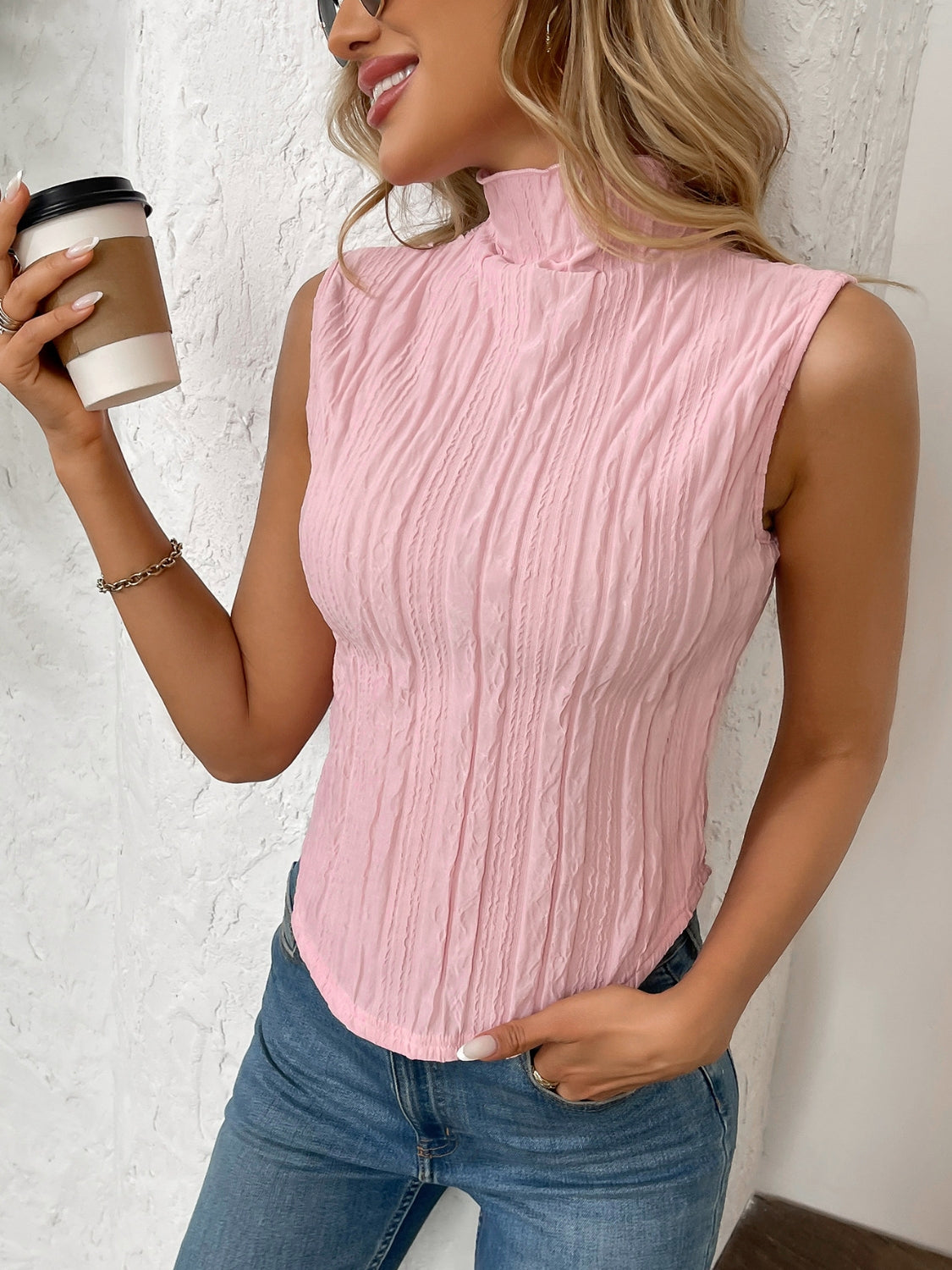 Textured sleeveless mock neck top in blush pink with vertical crinkle pattern.