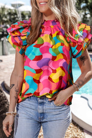Kaleidoscope ruffle sleeve smocked blouse in hot pink with a colorful abstract print.