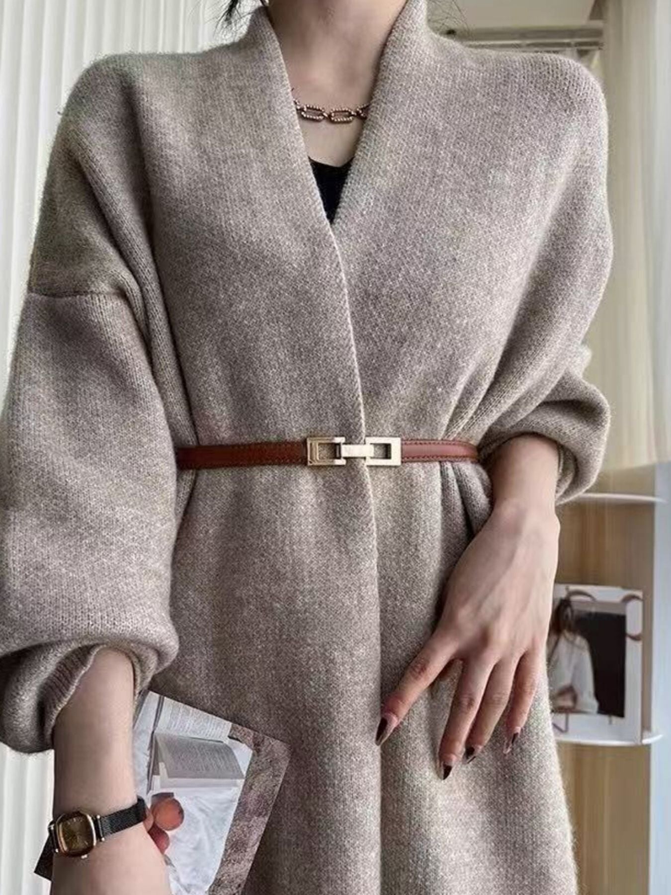 Brown cowhide leather belt with gold buckle cinching a cardigan