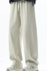 Men's beige loose fit sweatpants with drawstring and curved seam detail.