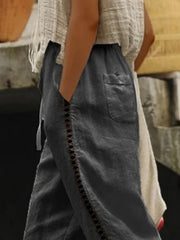 Dark gray relaxed cropped pants with hollow out trim detail and pockets.