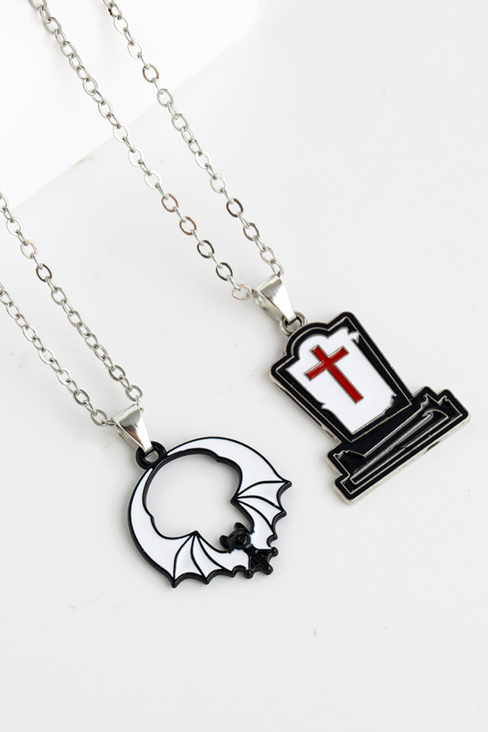 Spooky Season enamel pendant necklaces: tombstone with red cross and bat outline.