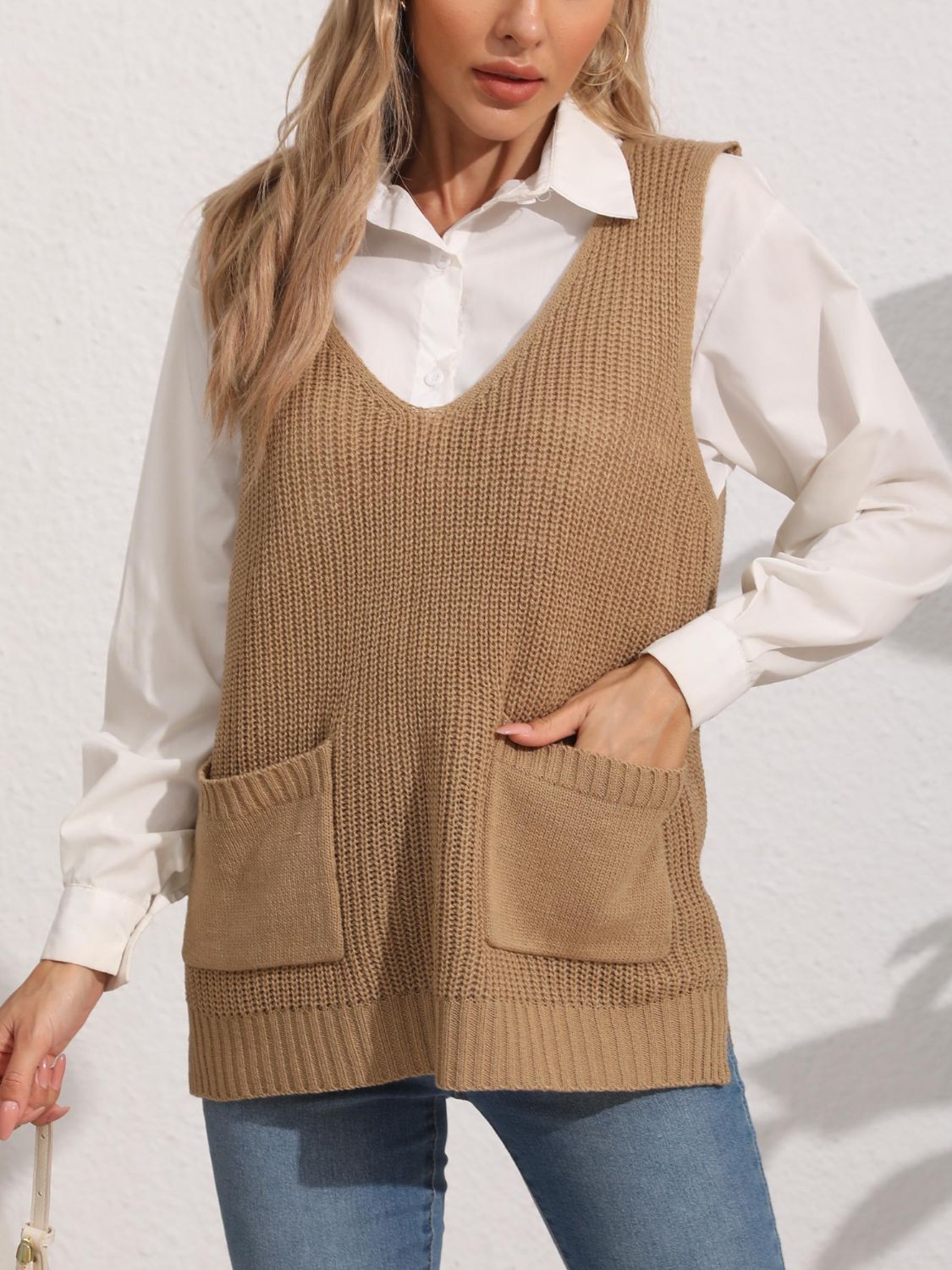 Camel oversized knit vest with V-neck and patch pockets, styled over a white shirt.