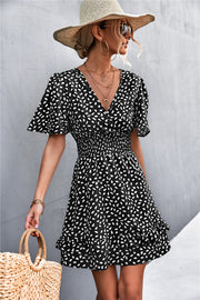 Black smocked waist mini dress with white speckle print, flutter sleeves and ruffled hem.
